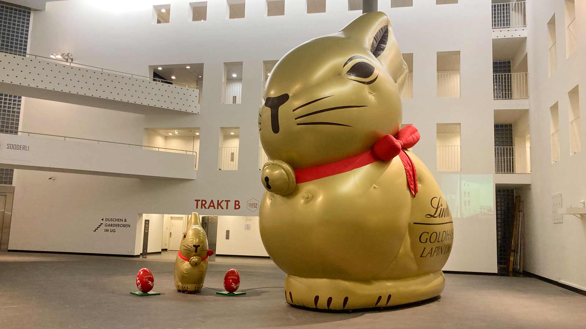 Aufblasbarer Werbeträger in Form eines goldigen riesigen Osterhasen steht in einem Geschäftshaus in der Halle