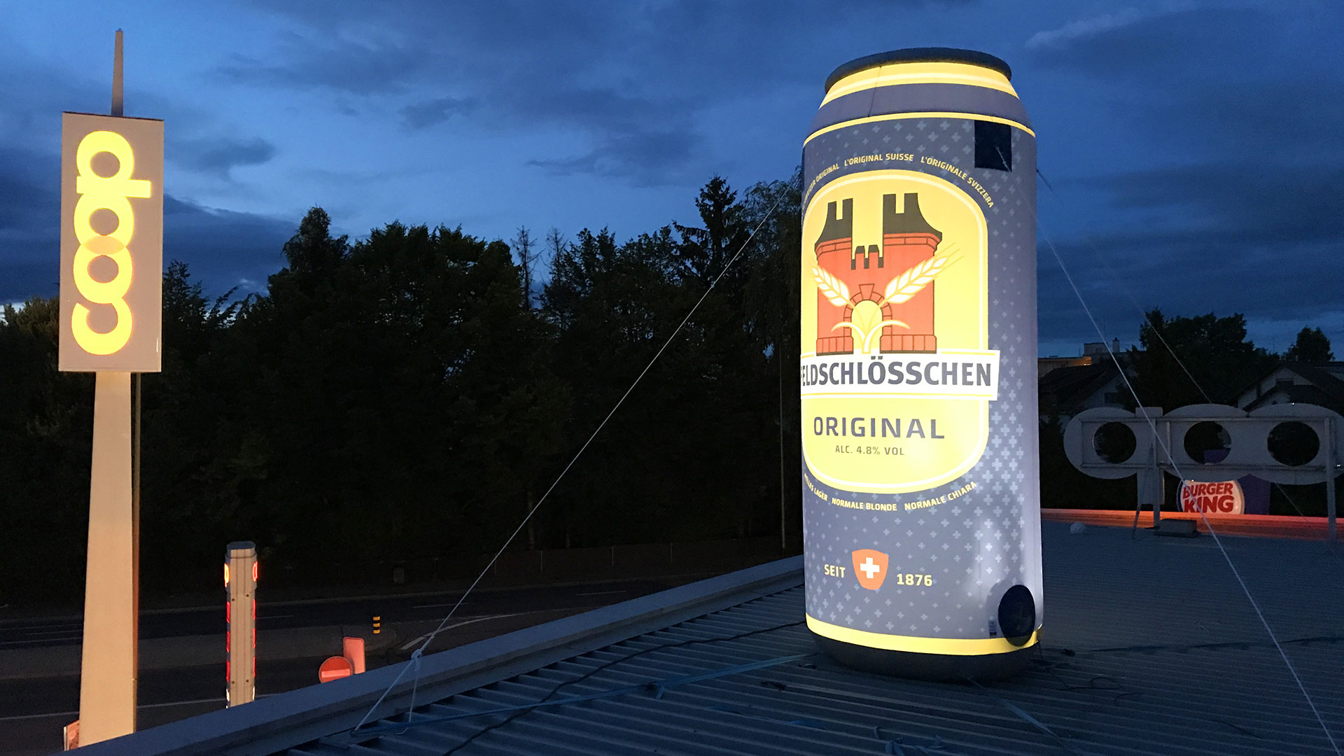 aufblasbare beleuchtete Bierdose von Feldschlösschen steht auf dem Dach von COOP und erweckt die Aufmerksamkeit auf sich
